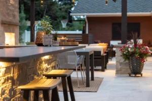 Modern Colorado outdoor living patio with a stone bar, dining area, decorative lighting, and container plants